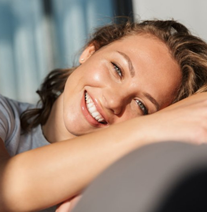 Woman in dental chair holding her cheek in pain