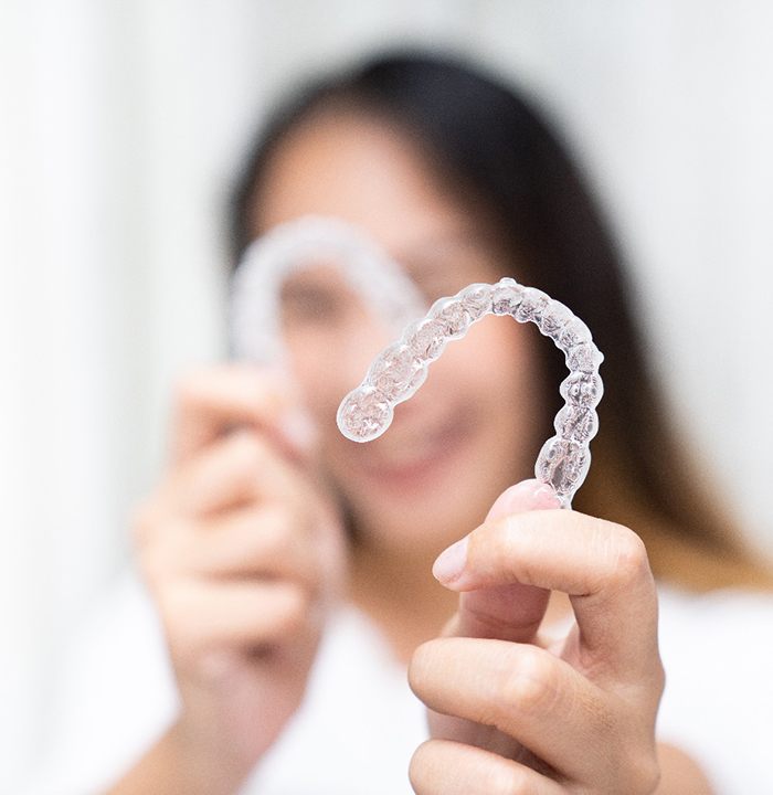 Patient smiling while holding up clear aligners