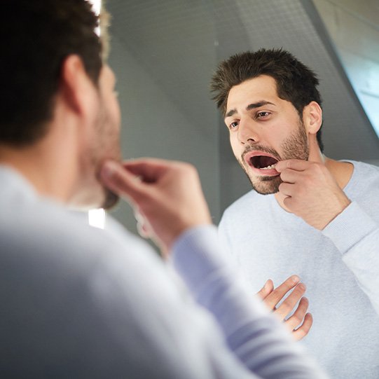 a man looking at his teeth in a mirror