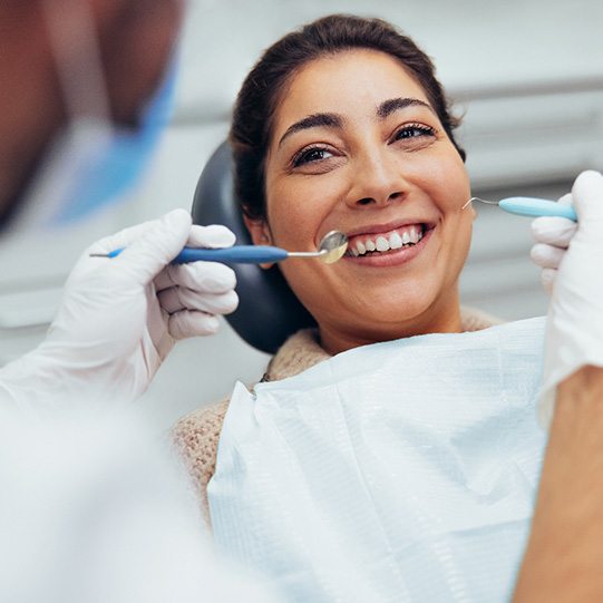 a woman smiling and having her teeth cleaned