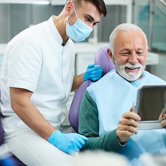 a smiling man looking in a mirror in the dental office