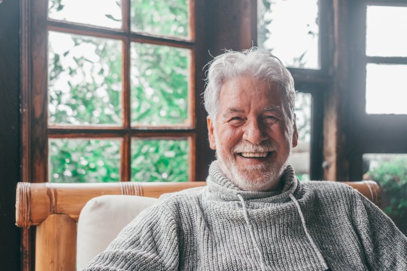 an older man smiling while sitting at home