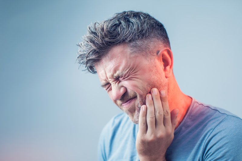 patient with dental emergency holding their cheek